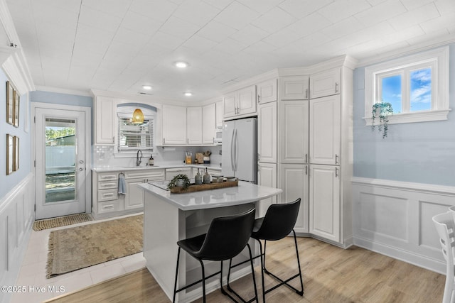125 NE 13th St, Oak Island, NC 28465 - kitchen featuring white appliances, light countertops, a decorative wall, white cabinetry, and a kitchen bar