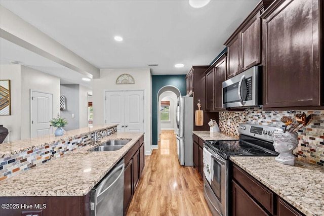 621 Longleaf Rd, Aberdeen, NC 28315 - kitchen featuring appliances with stainless steel finishes, light wood-style floors, dark brown cabinetry, backsplash, and arched walkways