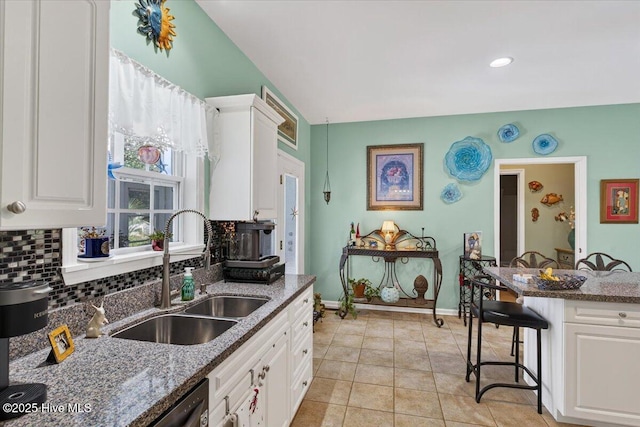 104 NE 27th St, Oak Island, NC 28465 - kitchen featuring decorative backsplash, white cabinets, a breakfast bar, and dark stone counters