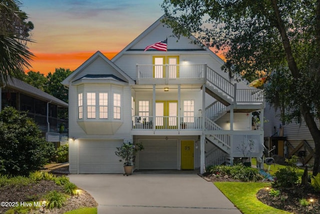 104 NE 27th St, Oak Island, NC 28465 - beach home featuring stairway, an attached garage, french doors, a balcony, and concrete driveway