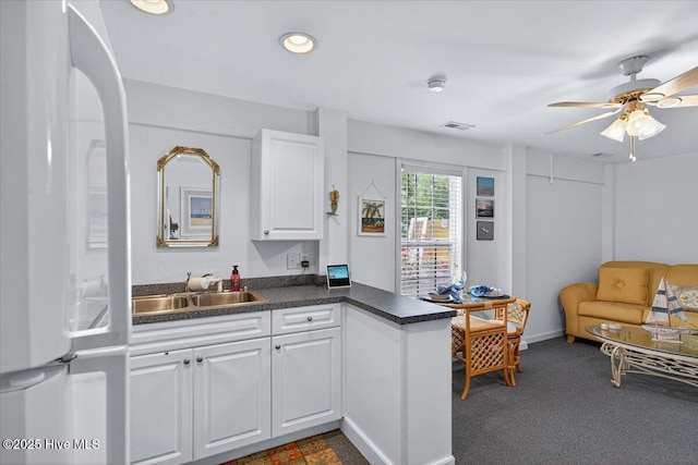 104 NE 27th St, Oak Island, NC 28465 - kitchen featuring dark countertops, fridge, white cabinets, ceiling fan, and recessed lighting