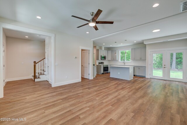 1536 Dorsey Ln, Navassa, NC 28451 - unfurnished living room with light wood finished floors, stairs, a ceiling fan, recessed lighting, and french doors