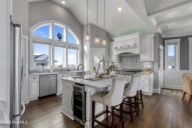 611 New River Inlet Rd, North Topsail Beach, NC 28460 - kitchen with stainless steel appliances, wine cooler, white cabinetry, an island with sink, and light stone counters