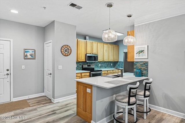 280 Woodlands Way Unit 5, Calabash, NC 28467 - kitchen with appliances with stainless steel finishes, decorative backsplash, light wood-style floors, a peninsula, and a breakfast bar