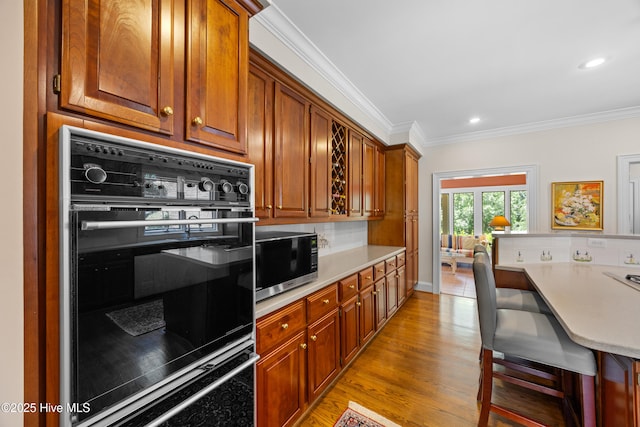 2000 Marsh Harbor Pl, Wilmington, NC 28405 - kitchen with stainless steel microwave, oven, light countertops, ornamental molding, and light wood finished floors