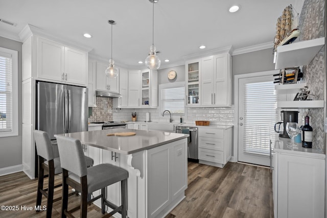 130 Raleigh St, Holden Beach, NC 28462 - kitchen featuring stainless steel appliances, under cabinet range hood, white cabinets, crown molding, and recessed lighting