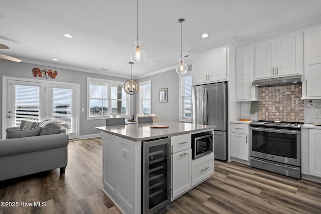 130 Raleigh St, Holden Beach, NC 28462 - kitchen with wine cooler, appliances with stainless steel finishes, under cabinet range hood, ornamental molding, and light countertops
