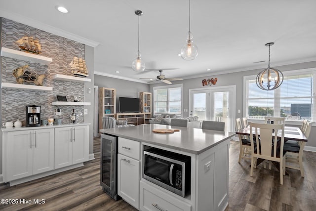 130 Raleigh St, Holden Beach, NC 28462 - kitchen featuring stainless steel microwave, beverage cooler, crown molding, plenty of natural light, and open shelves