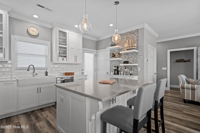 130 Raleigh St, Holden Beach, NC 28462 - kitchen featuring backsplash, dark wood-style floors, white cabinetry, ornamental molding, and recessed lighting