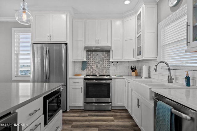 130 Raleigh St, Holden Beach, NC 28462 - kitchen with stainless steel appliances, ornamental molding, white cabinetry, backsplash, and glass insert cabinets