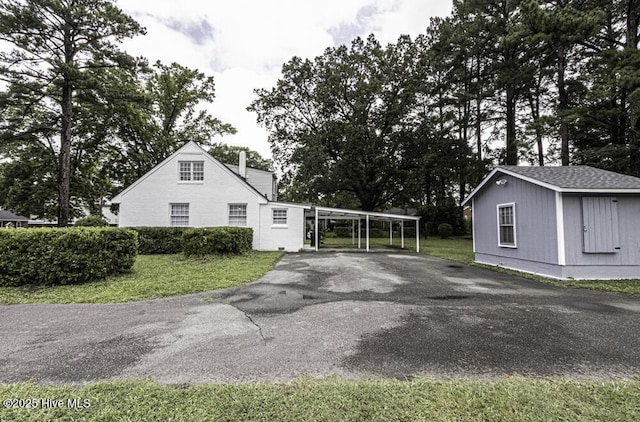 309 Mcgwigan St, Enfield, NC 27823 - view of property exterior featuring driveway, a yard, a chimney, and view of scattered trees