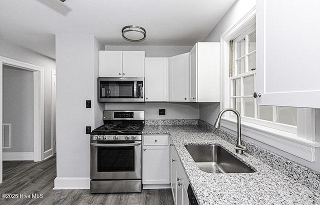309 Mcgwigan St, Enfield, NC 27823 - kitchen with appliances with stainless steel finishes, white cabinetry, light stone countertops, and dark wood-type flooring