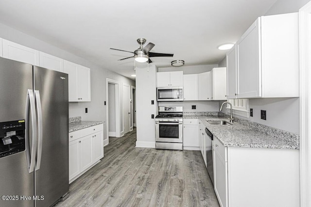 309 Mcgwigan St, Enfield, NC 27823 - kitchen featuring appliances with stainless steel finishes, a ceiling fan, light wood-style flooring, white cabinets, and light stone counters