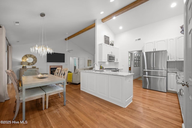 118 Tremayne Dr, New Bern, NC 28560 - kitchen featuring stainless steel appliances, beamed ceiling, white cabinetry, a fireplace, and high vaulted ceiling