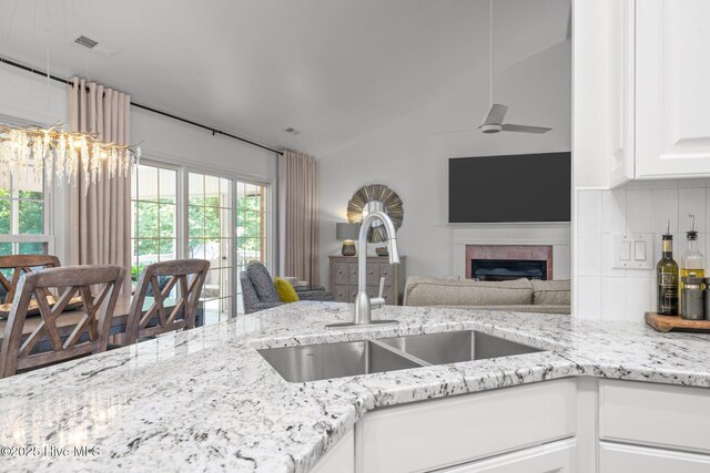 118 Tremayne Dr, New Bern, NC 28560 - kitchen with open floor plan, a fireplace, light stone counters, ceiling fan, and white cabinetry
