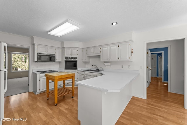 15 Magnolia Ave, Pinehurst, NC 28374 - kitchen featuring black appliances, light countertops, light wood-style floors, a peninsula, and crown molding