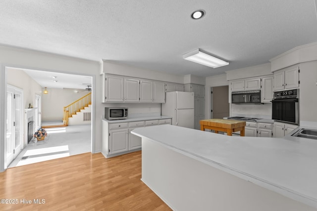 15 Magnolia Ave, Pinehurst, NC 28374 - kitchen with black appliances, a textured ceiling, light countertops, light wood-type flooring, and a ceiling fan