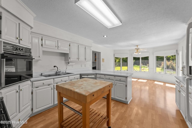 15 Magnolia Ave, Pinehurst, NC 28374 - kitchen featuring black oven, a peninsula, a textured ceiling, stainless steel dishwasher, and light wood finished floors