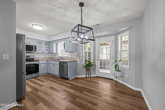 1134 Tebo Rd, New Bern, NC 28562 - kitchen featuring appliances with stainless steel finishes, gray cabinets, a chandelier, dark wood-style floors, and glass insert cabinets