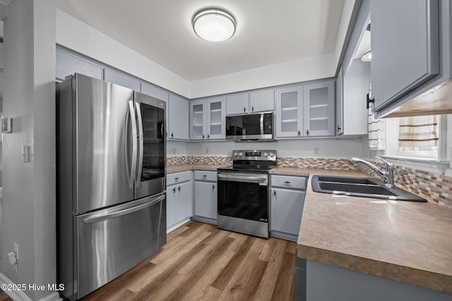 1134 Tebo Rd, New Bern, NC 28562 - kitchen with appliances with stainless steel finishes, gray cabinetry, light wood-style floors, and glass insert cabinets