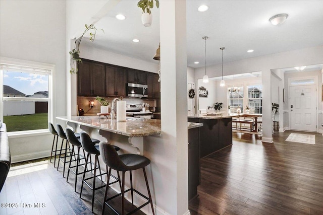 108 Bernier Ct, Princeton, NC 27569 - kitchen with stainless steel microwave, range, dark brown cabinetry, dark wood finished floors, and a breakfast bar