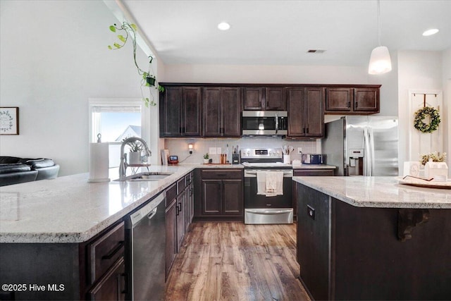 108 Bernier Ct, Princeton, NC 27569 - kitchen with stainless steel appliances, dark brown cabinets, light wood-style flooring, light stone counters, and a peninsula