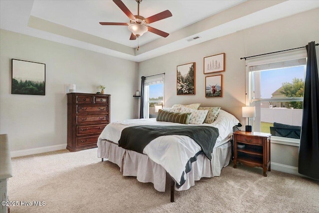 108 Bernier Ct, Princeton, NC 27569 - bedroom featuring a tray ceiling, light colored carpet, multiple windows, and a ceiling fan