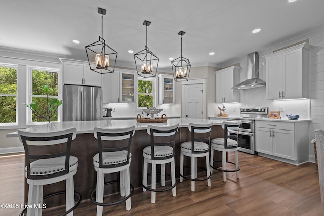 8805 Sound View Ct, Emerald Isle, NC 28594 - kitchen with wall chimney exhaust hood, appliances with stainless steel finishes, plenty of natural light, recessed lighting, and a kitchen island