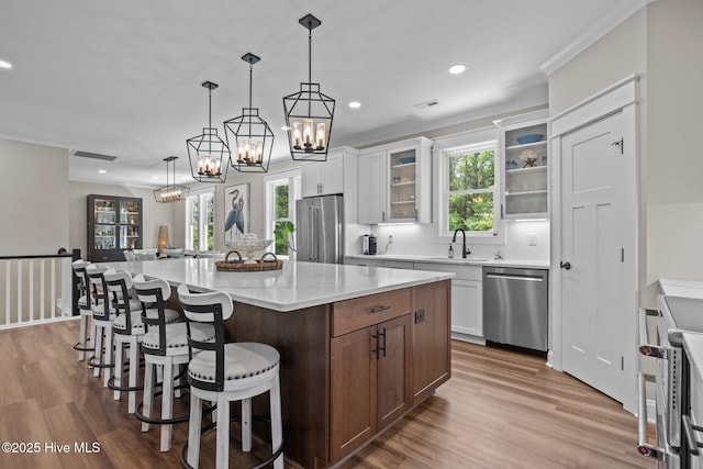 8805 Sound View Ct, Emerald Isle, NC 28594 - kitchen with appliances with stainless steel finishes, light wood finished floors, recessed lighting, a chandelier, and glass insert cabinets