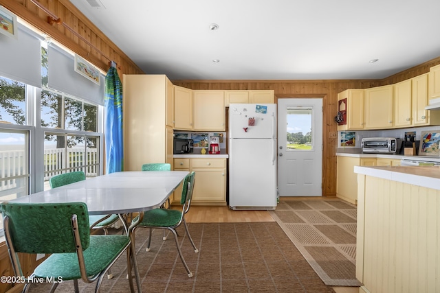 124 Holiday Knl, Hertford, NC 27944 - kitchen featuring freestanding refrigerator, light wood-style floors, light countertops, black microwave, and wood walls