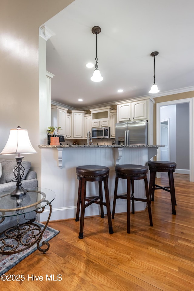 404 River Birch Dr, Greenville, NC 27858 - kitchen featuring stainless steel appliances, a breakfast bar area, stone counters, crown molding, and a peninsula