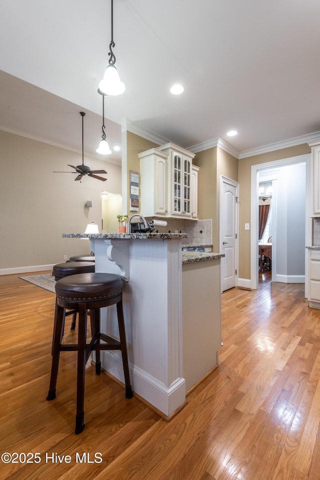 404 River Birch Dr, Greenville, NC 27858 - kitchen featuring crown molding, glass insert cabinets, stone counters, a breakfast bar area, and ceiling fan