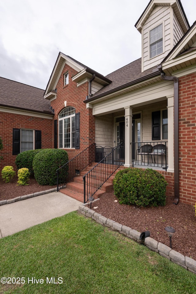 404 River Birch Dr, Greenville, NC 27858 - view of front of home with a shingled roof, brick siding, a porch, and a front yard