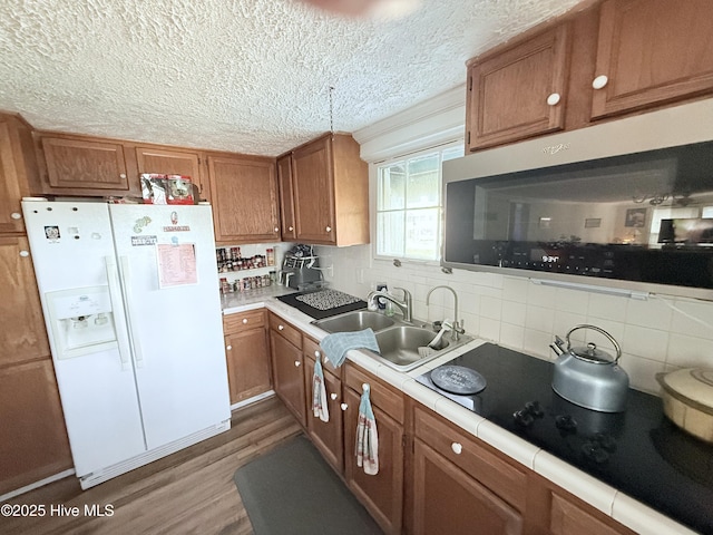 200 Carolina Beach Ave S, Carolina Beach, NC 28428 - kitchen featuring white refrigerator with ice dispenser, tile counters, brown cabinets, wood finished floors, and a textured ceiling