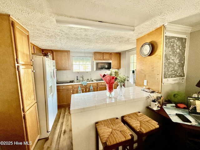 200 Carolina Beach Ave S, Carolina Beach, NC 28428 - kitchen featuring white appliances, tile countertops, a textured ceiling, a peninsula, and brown cabinetry