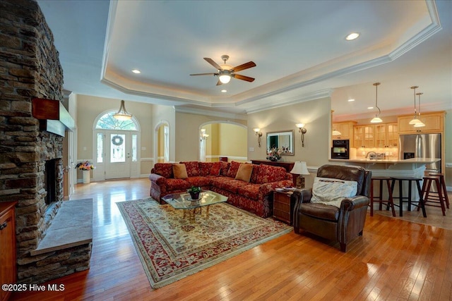 100 Knollwood Ct, New Bern, NC 28562 - living room featuring a tray ceiling, light wood-style flooring, ceiling fan, a fireplace, and crown molding