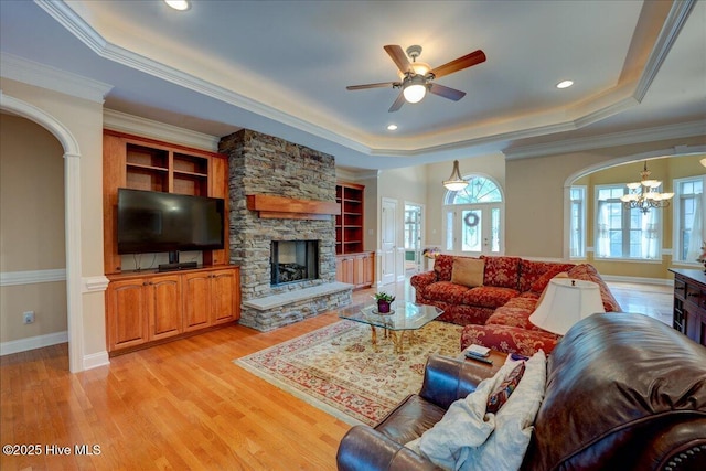 100 Knollwood Ct, New Bern, NC 28562 - living room featuring a raised ceiling, arched walkways, a chandelier, a stone fireplace, and light wood-style floors