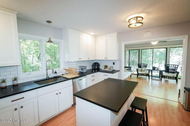254 W Devonshire Ave, West End, NC 27376 - kitchen with dark countertops, light wood-style floors, white cabinetry, a kitchen breakfast bar, and a textured ceiling