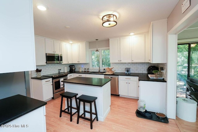 254 W Devonshire Ave, West End, NC 27376 - kitchen with appliances with stainless steel finishes, plenty of natural light, dark countertops, and white cabinetry