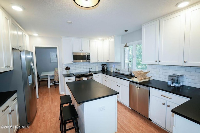 254 W Devonshire Ave, West End, NC 27376 - kitchen with stainless steel appliances, dark countertops, light wood finished floors, and white cabinets