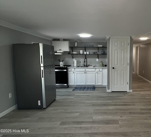510 S Sycamore St, Fremont, NC 27830 - kitchen with freestanding refrigerator, electric range, under cabinet range hood, ornamental molding, and white cabinetry