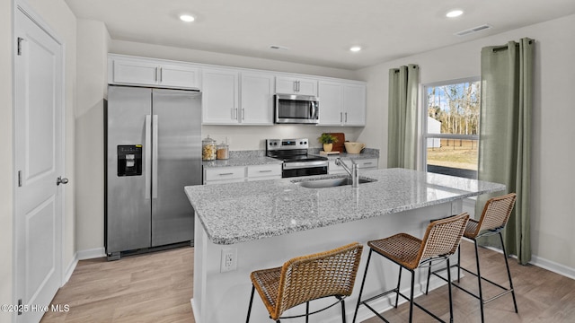 205 Wood St, La Grange, NC 28551 - kitchen with appliances with stainless steel finishes, white cabinets, a center island with sink, light wood finished floors, and recessed lighting