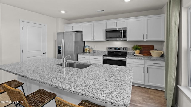 205 Wood St, La Grange, NC 28551 - kitchen with stainless steel appliances, a breakfast bar, white cabinets, wood finished floors, and light stone countertops