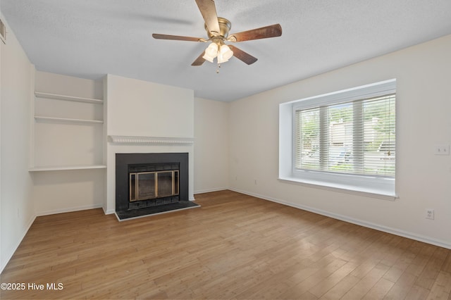 514 Cobblestone Dr, Wilmington, NC 28405 - unfurnished living room featuring light wood-style floors, a ceiling fan, a textured ceiling, and a glass covered fireplace