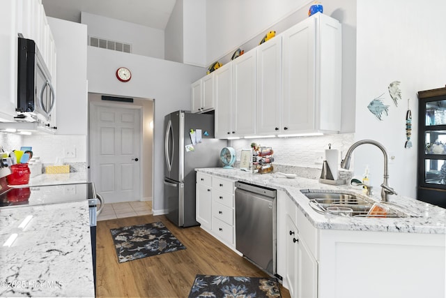 102 Crooked Gulley Cir, Sunset Beach, NC 28468 - kitchen with stainless steel appliances, a high ceiling, white cabinetry, tasteful backsplash, and wood finished floors