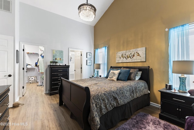 102 Crooked Gulley Cir, Sunset Beach, NC 28468 - bedroom with high vaulted ceiling, a walk in closet, a chandelier, light wood finished floors, and a closet
