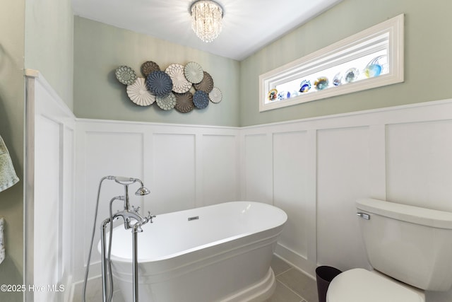 102 Crooked Gulley Cir, Sunset Beach, NC 28468 - bathroom featuring a decorative wall, a freestanding tub, wainscoting, a chandelier, and tile patterned floors