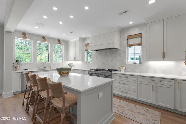 4139 Cobleskill Dr, Leland, NC 28451 - kitchen featuring high end range, dishwashing machine, backsplash, a kitchen island, and a kitchen bar