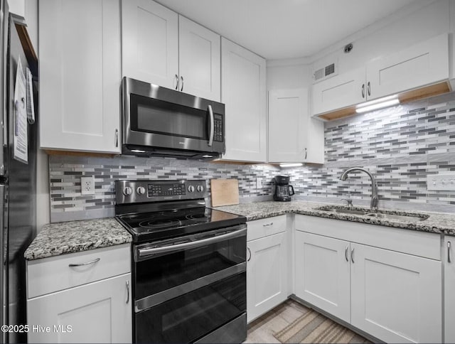 1896 New River Inlet Rd Unit 1310, North Topsail Beach, NC 28460 - kitchen featuring stainless steel microwave, black electric range, freestanding refrigerator, white cabinetry, and backsplash