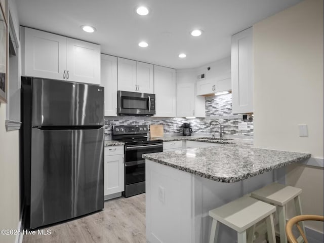 1896 New River Inlet Rd Unit 1310, North Topsail Beach, NC 28460 - kitchen with stainless steel appliances, a peninsula, light stone countertops, white cabinets, and a breakfast bar area